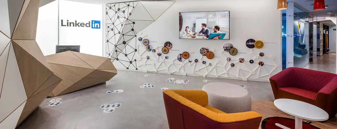 Reception and common area of the LinkedIn project with corporate design, geometric counter, waiting furniture and graphic elements integrated into the wall.